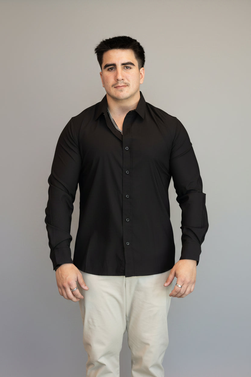 Man wearing a black shirt and light-colored pants against a grey background