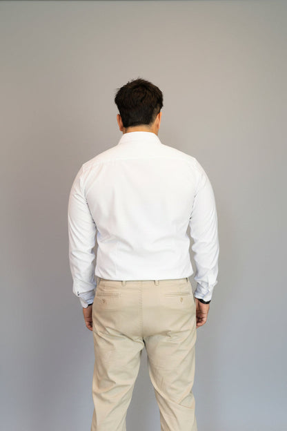Man wearing a white shirt and beige pants against a blue background