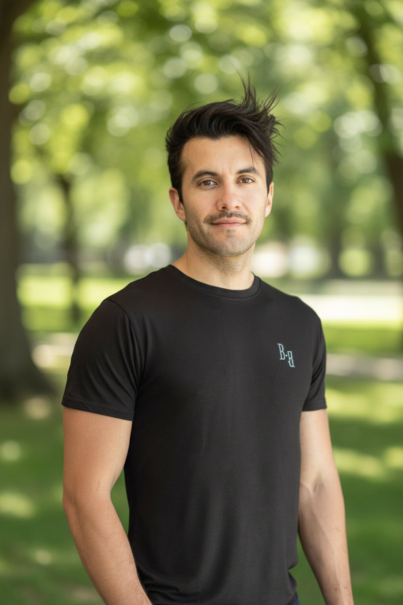 Man wearing a black B.Balanced Co bamboo blend Everyday Tee with four-way stretch in a park setting