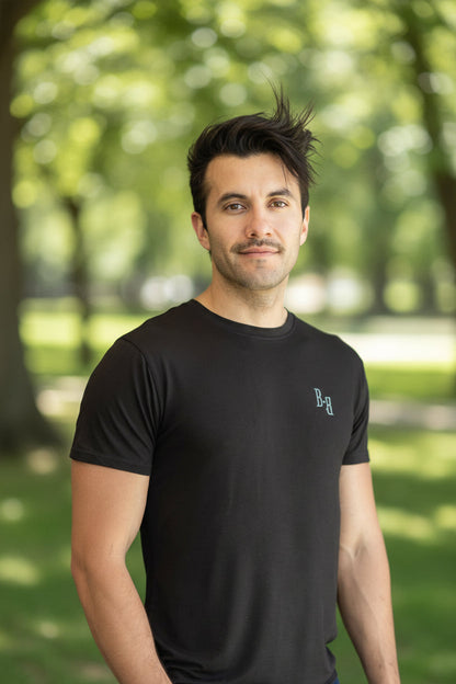 Man wearing a black B.Balanced Co bamboo blend Everyday Tee with four-way stretch in a park setting